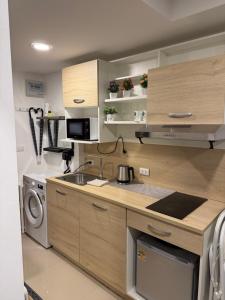 a kitchen with wooden cabinets and a sink and a stove at Sunset view apartment with a pool MAIKHAO Phuket in Ban Mai Salae