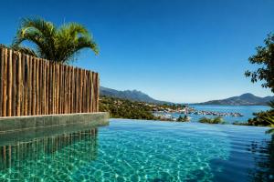 a swimming pool with a fence and a view of the water at Vila Bambu Ilhabela, Santa Tereza in Ilhabela