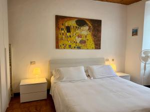 a bedroom with a white bed and a painting on the wall at The Nest in Mandello del Lario
