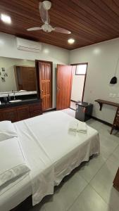 a large white bed in a room with a kitchen at Suítes Aymoré in Itacaré