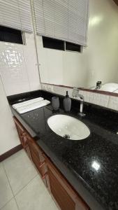 a bathroom with a black counter and a sink at Suítes Aymoré in Itacaré