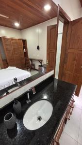 a bathroom with a sink and a bed at Suítes Aymoré in Itacaré