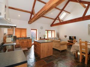 a large kitchen and living room with wooden beams at Riverside Barn in Gilwern