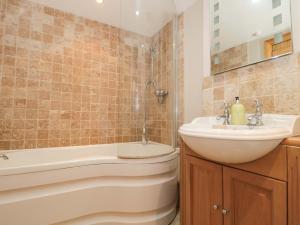 a bathroom with a sink and a tub and a toilet at Riverside Barn in Gilwern +19 photos