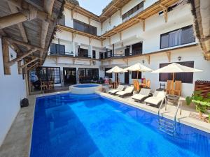 a pool with chairs and umbrellas next to a building at Hostal Brisas del Mar in Punta Negra
