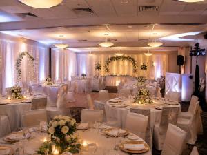 a banquet hall with white tables and white chairs at Ocean Landings Resort Cocoa Beach Port Canaveral in Cocoa Beach