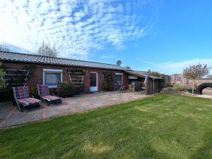a brick house with two chairs on a patio at Nordseehof Reitz in Friedrichskoog
