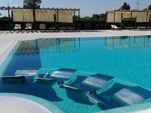 two chairs in a swimming pool with blue water at Hotel Villa Cornér della Regina - Buongiorno! Hotels in Vedelago
