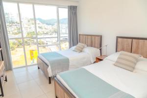a hotel room with two beds and a large window at Ocean View Condo with Resort Amenities in Acapulco +43 photos