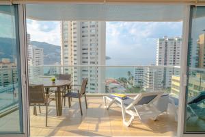 a balcony with a table and chairs and a view of the city at Ocean View Condo with Resort Amenities in Acapulco