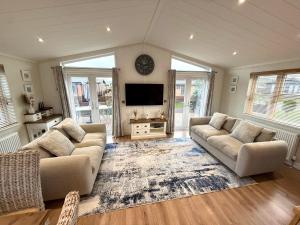 a living room with two couches and a flat screen tv at Lodge 18 - The Pines in Saltburn-by-the-Sea