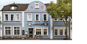 un gran edificio azul con mesas y sillas delante de él en Mühlenkamp Hotel & Gastronomie, en Oelde