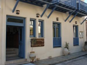 un edificio con ventanas azules y un cartel en él en Xenonas Afroditi, en Loutra