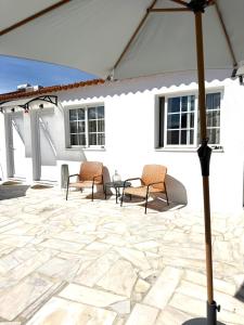 a patio with chairs and a table and an umbrella at Casa da Calma - GUESTHOUSE in Alandroal