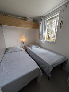 two beds in a small room with a window at Bungalow mahi-mahi in Lacanau