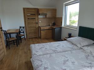 a bedroom with a bed and a table and a kitchen at u Harrego in Dębki