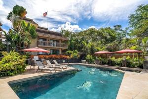 a swimming pool with chairs and umbrellas in front of a house at KONA - Royal Kahili B205 End Unit - Gorgeous Views in Kailua-Kona