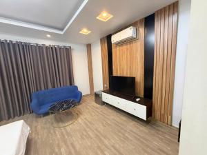 a living room with a blue chair and a television at G9 home hotel in Hanoi