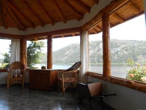 a room with windows and chairs and a view of the water at Cabañas El Muelle in Cholila