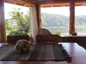a room with a large window and a table with flowers at Cabañas El Muelle in Cholila +2 photos