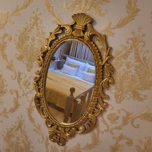 a gold mirror on a wall with a bed at Jázmin Apartman in Debrecen