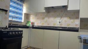 a kitchen with white cabinets and a counter top with bananas on the wall at Otunba's Crib in Gbogije +13 photos