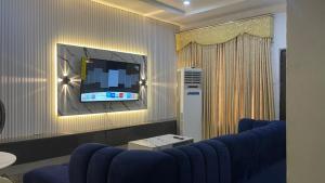 a living room with a blue couch and a tv at Otunba's Crib in Gbogije