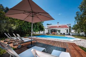 a patio with chairs and an umbrella next to a swimming pool at Quinta da Berlica - Alentejo in Estremoz