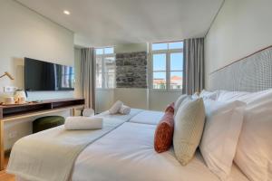 a bedroom with a large white bed with a television at Chapelaria Boutique Hotel in Funchal
