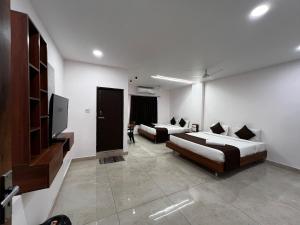 a room with two beds and a flat screen tv at Hotel Church Way Inn in Velankanni