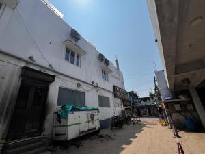 a white building on a street next to a building at Hotel Church Way Inn in Velankanni