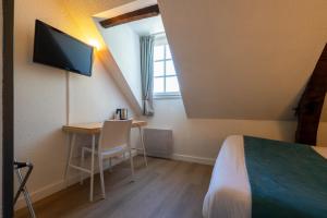 a room with a bed and a desk and a tv at Hôtel Le Blason in Amboise