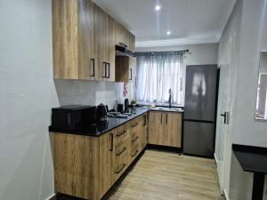 a kitchen with wooden cabinets and a black microwave at Casa Kruger Lodge in Phalaborwa