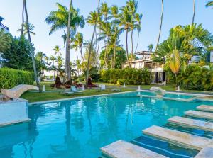 a resort swimming pool with palm trees in the background at apartement rooftop oceanfront - Hotel Aligio in Las Terrenas
