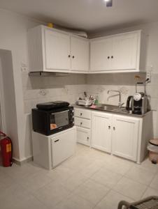 a kitchen with white cabinets and a sink and a stove at Aggeliki Homes paradosiako nisiotiko in Poros