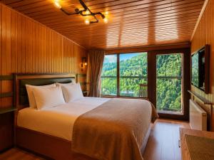 a bedroom with a bed and a large window at Ayder Doga Resort in Ayder Yaylasi