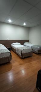 three beds in a room with wooden floors at Hotel La Costa in Rio de Janeiro