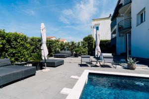 a patio with a swimming pool and umbrellas at Holiday Apartments Amarilis in Pakoštane
