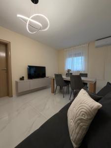 a living room with a couch and a table and a television at Villa Asa with private Jacuzzi in Vir