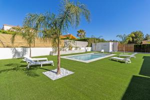 a yard with two benches and a palm tree at Oasis los Lagos in Alginet