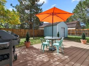 a patio with a table and chairs and an orange umbrella at Cozy Pet Friendly Big Bear Cabin in Big Bear City