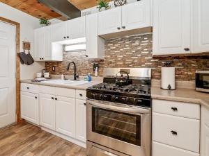 a kitchen with white cabinets and a stove top oven at Cozy Pet Friendly Big Bear Cabin in Big Bear City