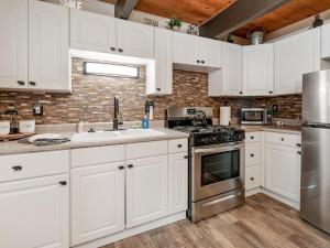 a kitchen with white cabinets and stainless steel appliances at Cozy Pet Friendly Big Bear Cabin in Big Bear City