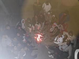 a group of people sitting around a fire at Raghupur trecking camp in Shoja