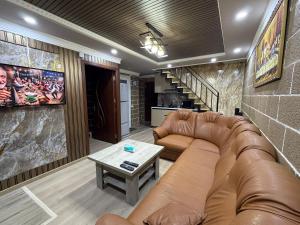 a living room with a leather couch and a table at BelGa Guest House in Gyumri