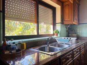 a kitchen counter with a sink and two windows at Casa de férias in Monte