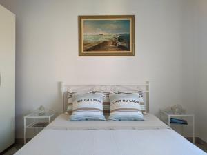 a white bed with a picture on the wall at Maréthias in Punta Marina