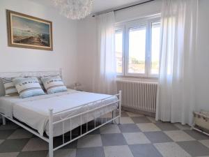 a white bedroom with a bed and a window at Maréthias in Punta Marina