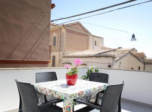 a table with chairs and a vase with flowers on a balcony at Bellamorèa in Noto