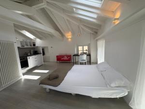 a large white bedroom with a large bed and a kitchen at Appartamento San Rocco in Intra